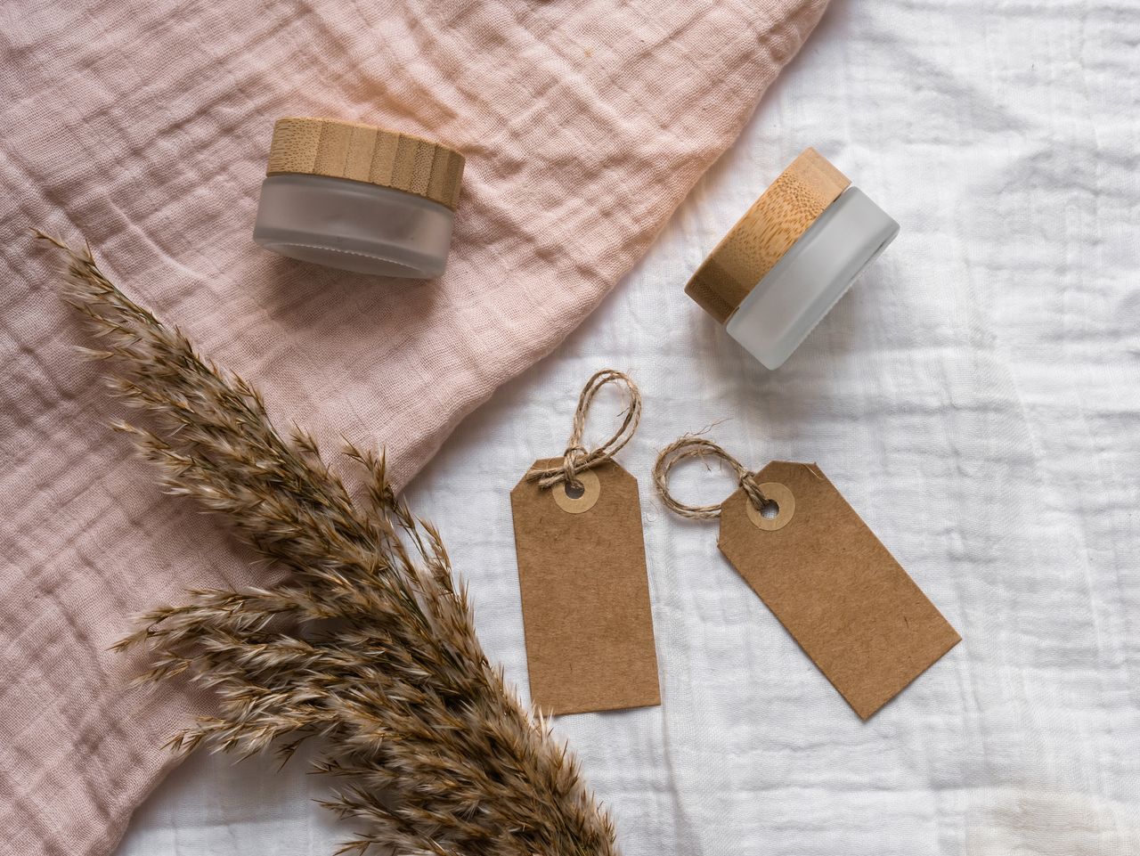 A rustic flatlay featuring jars with wooden lids and eco-friendly gift tags on textured fabric. Ideal for branding.