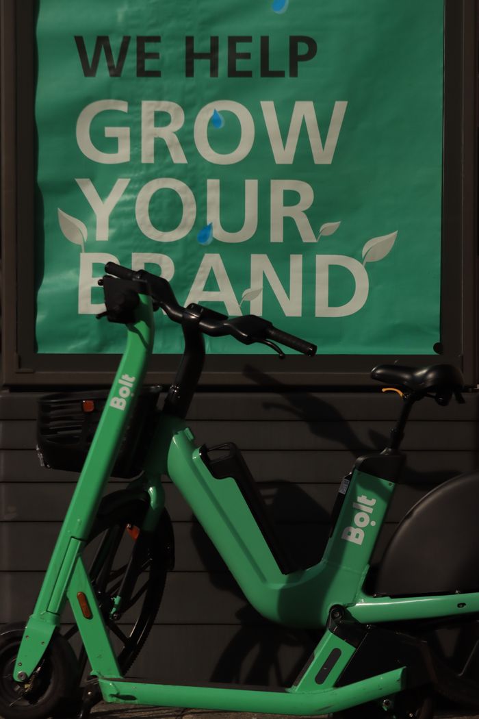 Un scooter électrique appuyé contre un mur, avec un slogan sur la croissance de la marque.